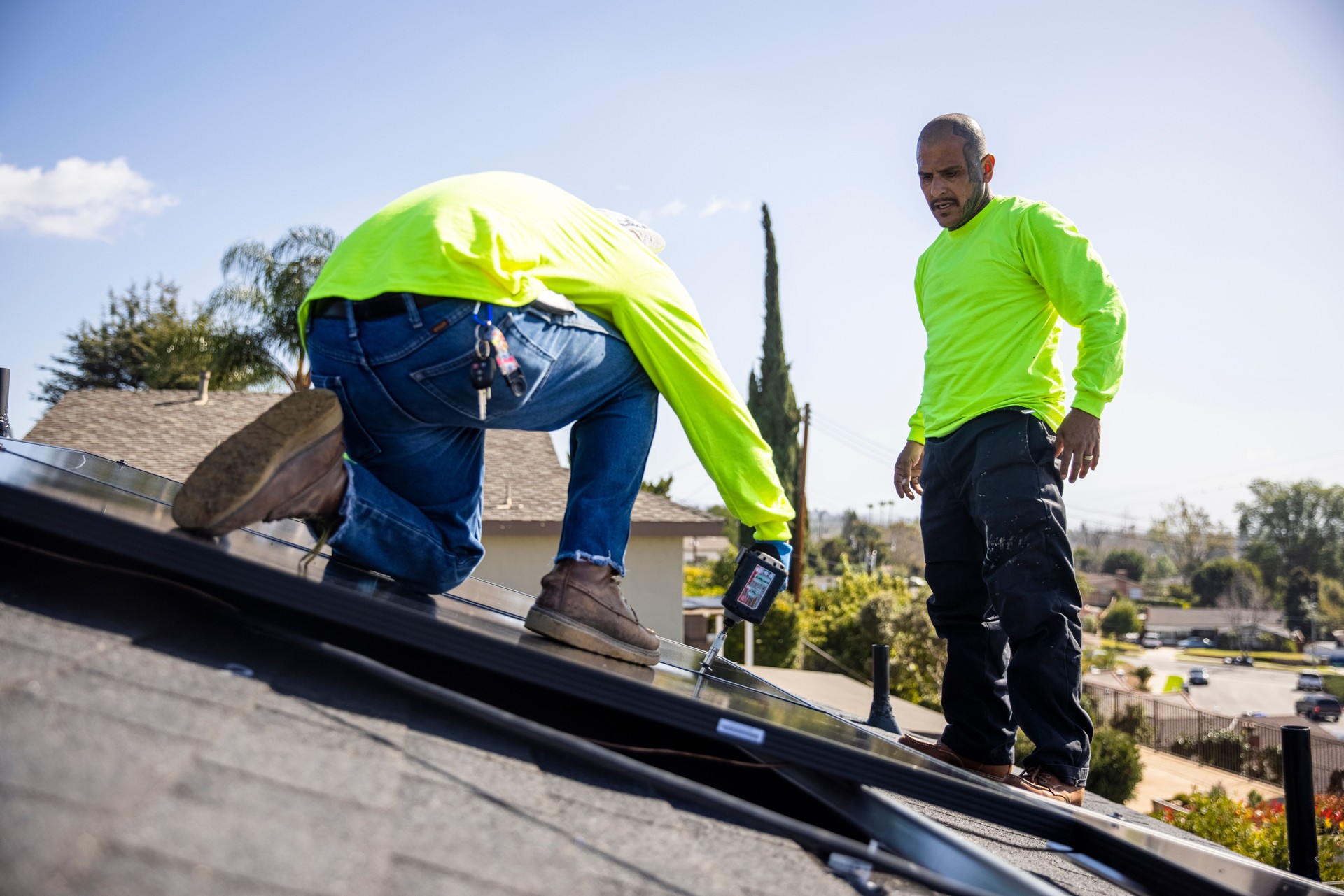Mexican Man Drilling Solar Panel to Roof